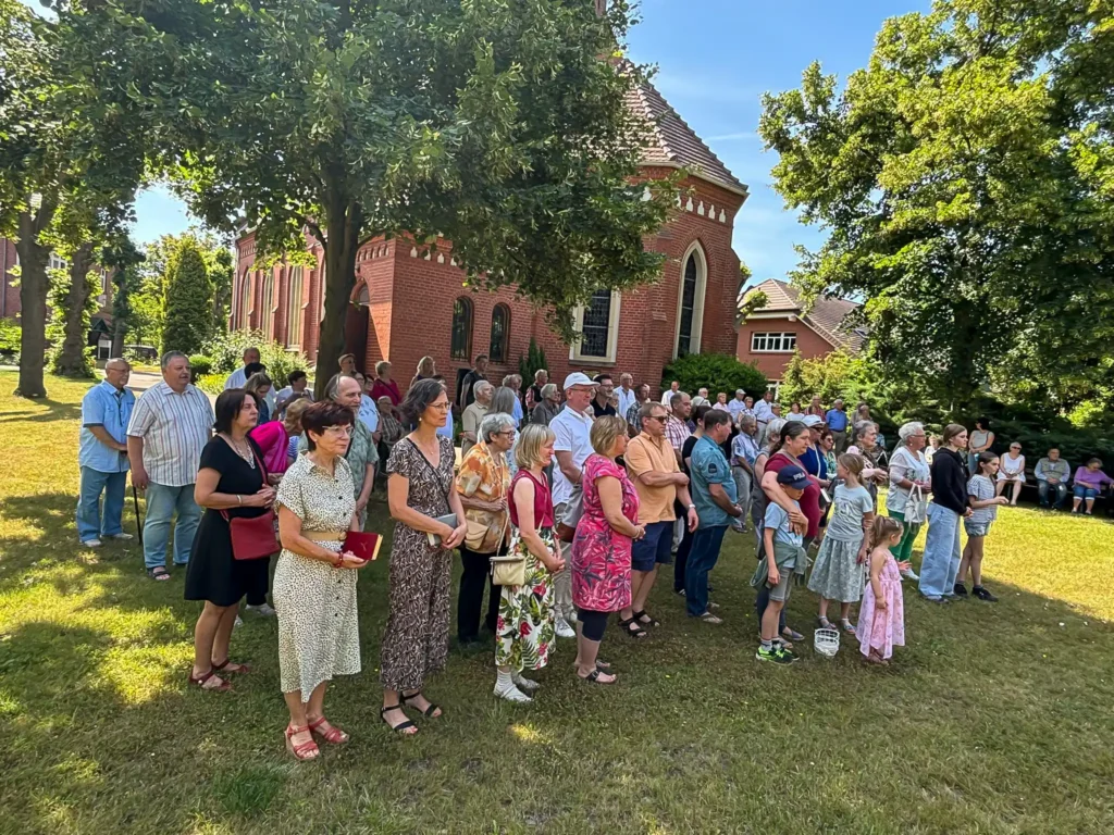 Gemeindemitglieder*innen im Garten hinter der Pfarrkirche