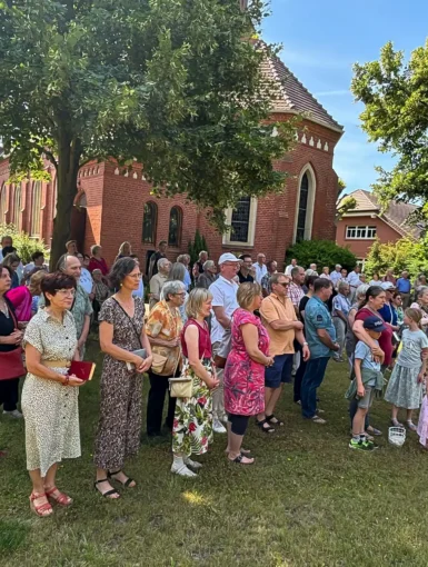 Gemeindemitglieder*innen im Garten hinter der Pfarrkirche