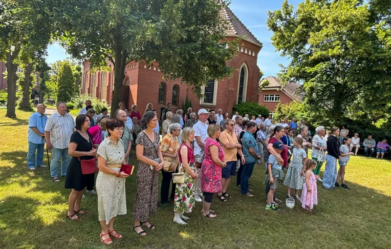 Gemeindemitglieder*innen im Garten hinter der Pfarrkirche